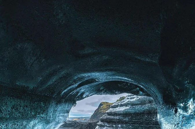 Un arco oscuro de cueva de hielo con luz del día entrando desde el otro lado