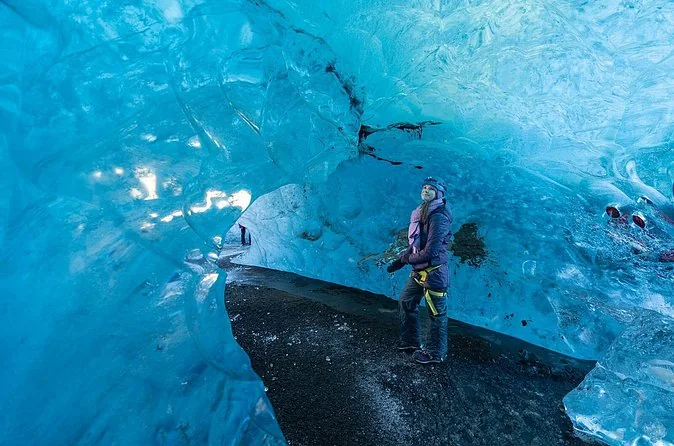 A bright blue Vatnajökull ice cave with a person standing inside
