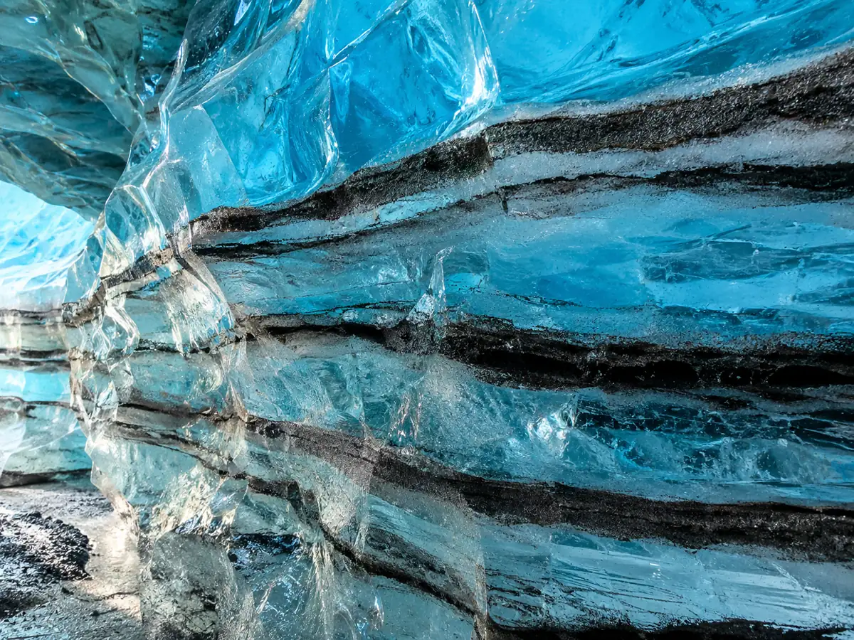 Blue glacier ice with sharp black stripes of volcanic ash frozen inside